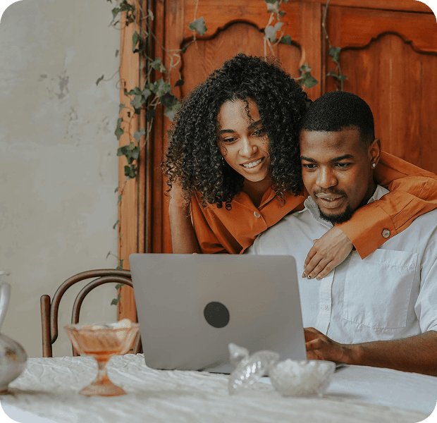 Couple smiling while reviewing options together on a laptop screen